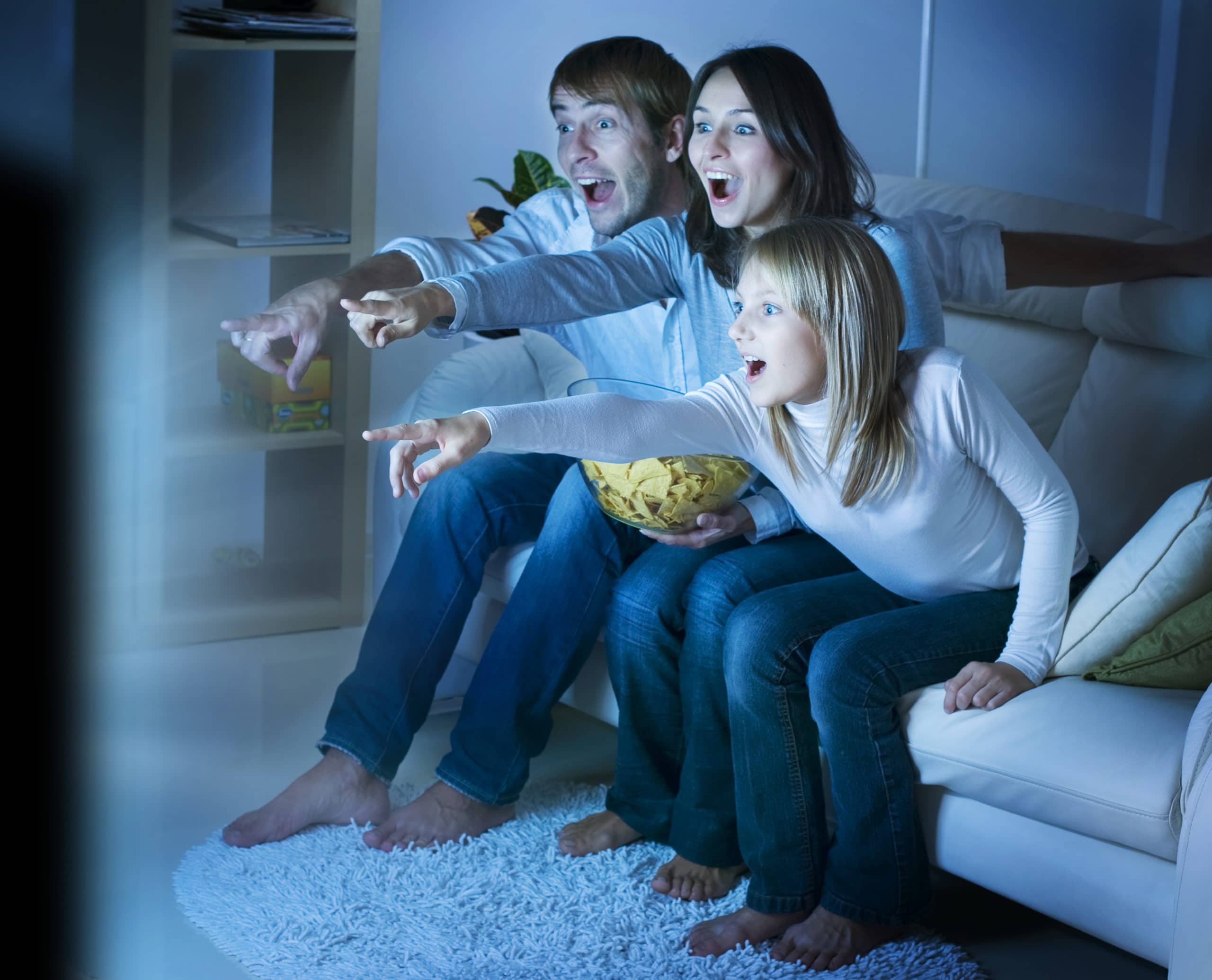 Family pointing at the tv from couch. Binge watching their favorite show