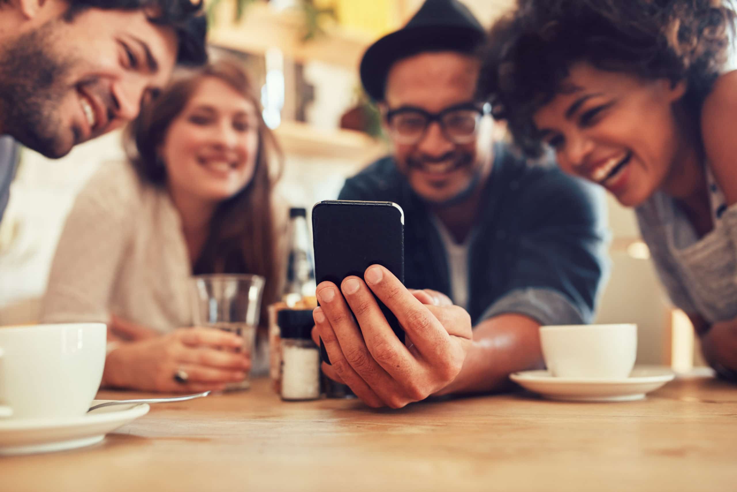 smiling friends looking at apartment reviews on mobile phone