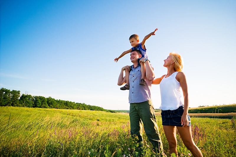 happy family outside with kid expanding arms