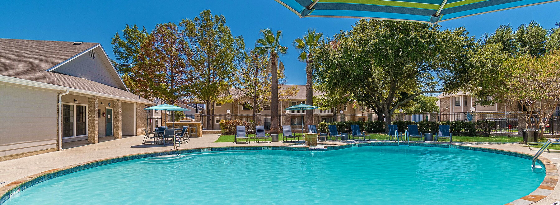 Image overlooking the community pool with the Amenity Center in the background surrounded by palm trees.
