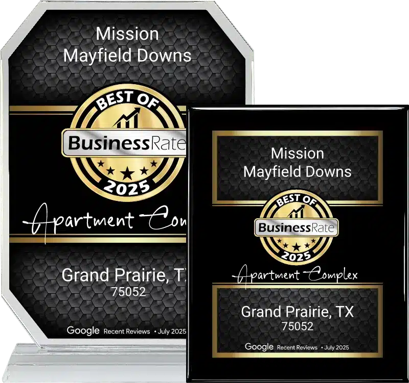 Two award plaques for Mission Mayfield Downs in Grand Prairie, TX, labeled "Best of 2025 Apartment Complex" from Business Rate, feature mission mayfield downs branding with striking gold and black design elements.