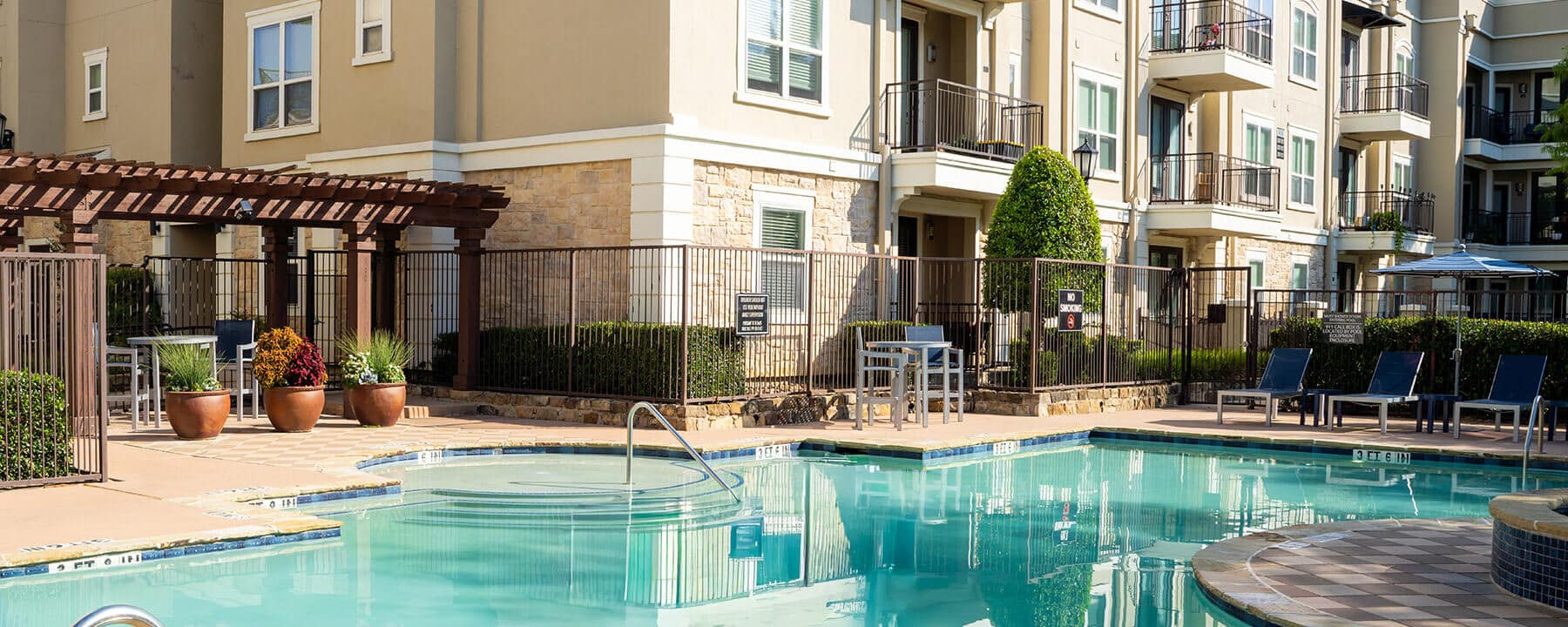 A swimming pool and hot tub in the Venue at Hometown courtyard, surrounded by a multi-story apartment building.